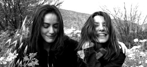 Two beautiful women laughing in a flower field